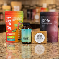 Collection of wellness products including a supplement bottle, soap bar, and two packaging on a reflective surface.