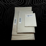 Stack of beige fabric sheets with 'Forever Natural' labels on a black background