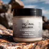 Jar of Primal Wellness Magnesium Arnica Tallow Balm on a rock with natural background