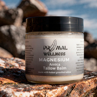 Jar of Primal Wellness Magnesium Arnica Tallow Balm on a rock with natural background
