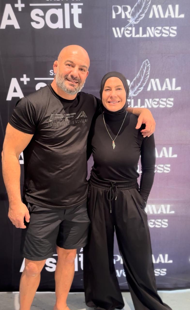 Two people posing together in front of a branded backdrop